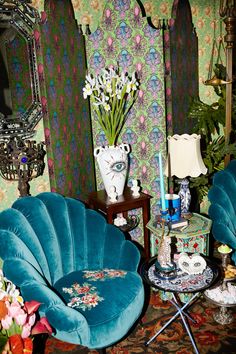 two blue chairs sitting next to each other in front of a wall with flowers on it