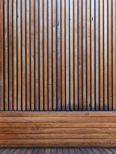 a wooden bench sitting in front of a wall with vertical slatted panels on it