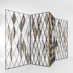 an open room divider with gold and black geometric designs on the sides, against a white background