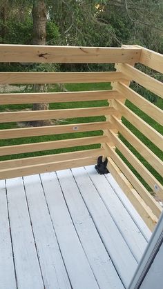 a black cat sitting on top of a wooden deck