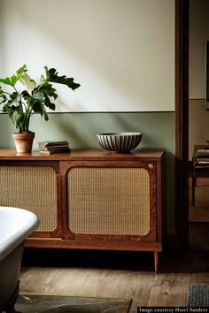 a potted plant sitting on top of a wooden cabinet next to a bath tub