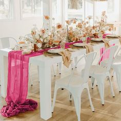 the table is set with white chairs and pink runneres on it, along with an assortment of flowers