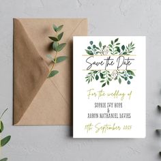 save the date card with greenery and gold foil on it next to an envelope