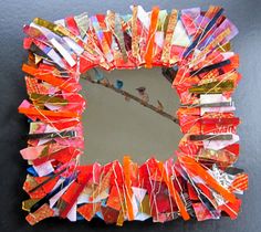 a mirror that has been made out of broken pieces of paper and colored strips on it