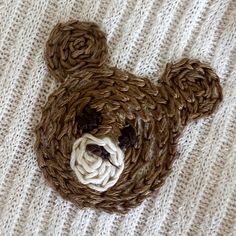 a teddy bear made out of yarn sitting on top of a blanket