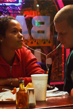 two people sitting at a table talking to each other