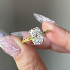 a woman's hand holding an engagement ring with clear acrylic nails on it