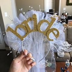 a person holding up a white and gold tiara with the word bride written on it