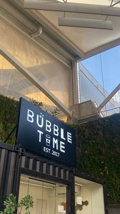 a sign that reads bubble time in front of a building with plants growing on it