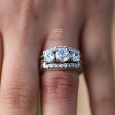 a woman's hand with two diamond rings on top of her wedding band,