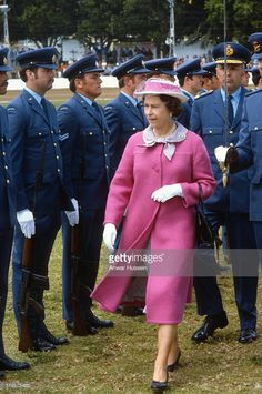 queen elizabeth in pink walking with other uniformed men and women at the royal palace on may 19, 2013 in london, england