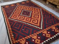 a red and black rug sitting on top of a white sheet covered floor next to a fire place