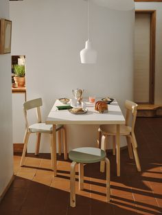 a white table with two chairs around it and food on the table next to it