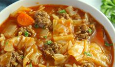 a white bowl filled with cabbage and meat soup on top of a blue table cloth