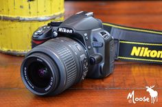 a nikon camera sitting on top of a wooden table next to a yellow can