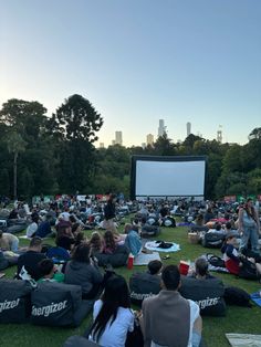 people are sitting on the grass watching a movie