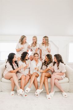 a group of women sitting on top of a couch drinking champagne together in front of the camera