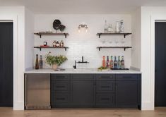 a kitchen with black cabinets and shelves filled with bottles