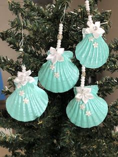 three seashell ornaments hanging from a christmas tree with white bows and pearls on them