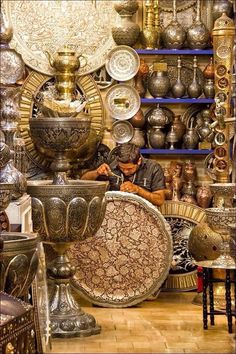 a man is working on an ornate vase in a room filled with many different items