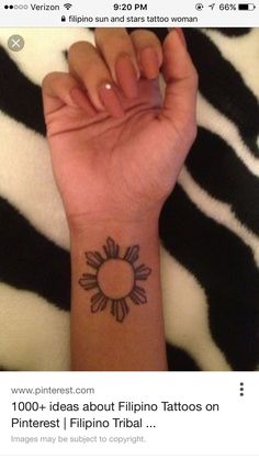 a woman's arm with a small sun tattoo on it