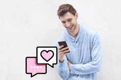 a man holding a smart phone in his hands and looking at the screen with hearts on it