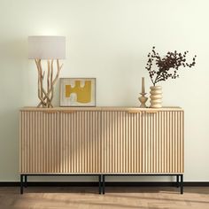 a wooden sideboard sitting on top of a hard wood floor next to a lamp