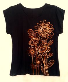 a black t - shirt with gold flowers on the front and back, sitting on a white surface