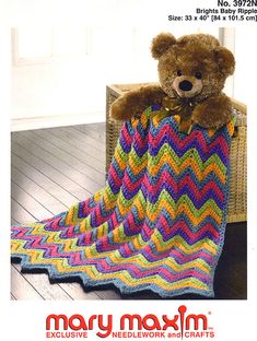 a teddy bear sitting on top of a crocheted blanket in the shape of a zigzag