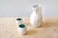 two white vases sitting on top of a wooden table