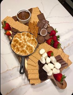 a platter filled with crackers, marshmallows and strawberries