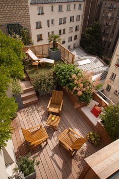 an aerial view of a wooden deck with chairs and tables on it, surrounded by greenery