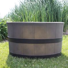 a large brown plastic tub sitting on top of a lush green grass covered field next to tall plants