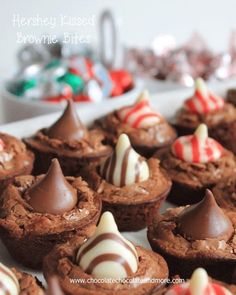 chocolate cupcakes with candy covered brownie bites on a white plate in front of christmas candies