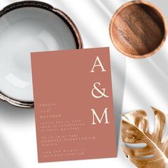 the wedding stationery is laid out on a table next to a bowl and plate