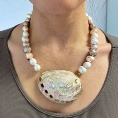 "Shell queen " This is a beautiful statement necklace made of chunky mop shell pearl beads . They have various colours mixed white, creamy and pink .  It is decorated with an xl  large  natural shell .  It is an impressive piece for extra ordinary looks . An ideal mermaid aesthetic piece Oval mop beads size aprox: 1x1.8 cm Irregular mop shell beads size aprox : 1.5-2 cm  Shell pendant length aprox 6-6.5  c/m  Necklace total length . one size / adjustable length .  Hypoallergenic/ sensitive frien Pearl White Shell Necklace With Pearl Pendant, White Mother Of Pearl Shell Necklace With Pearl Pendant, Pearl White Mother Of Pearl Shell Necklace Gift, Pearl White Mother Of Pearl Shell Necklace As Gift, Mother Of Pearl Shell Necklaces For Gifts, Elegant White Abalone Shell Jewelry, Mother Of Pearl Shell Necklace Gift, Single Strand Mother Of Pearl Necklace Gift, White Mother Of Pearl Pendant Shell Necklace