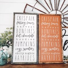 two wooden signs sitting next to each other on top of a table with flowers and plants