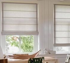 two windows with roman shades in a kitchen window sill next to a table and chair