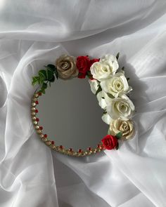 there is a mirror with roses and pearls on the wall next to white sheeted fabric