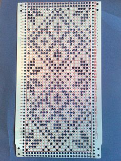 a cross stitch pattern is displayed on a blue tablecloth with white and black dots