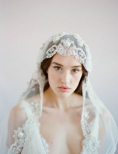 a woman wearing a veil over her head with a dress on it's shoulders