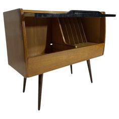 an old fashioned wooden cabinet with black glass top and metal handles on the bottom shelf