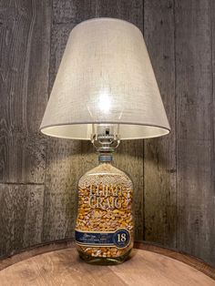 a lamp that is sitting on top of a wooden table next to a jar filled with peanuts