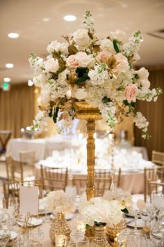 the tables are set up with white flowers and gold candelabras for an elegant wedding reception