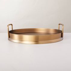 a round brass tray with handles on a white surface