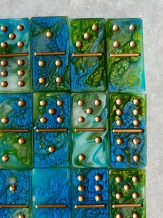 a blue and green tile with gold balls on it's sides, in the shape of squares