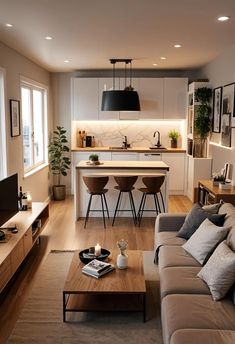 a living room filled with furniture and a flat screen tv mounted to the wall next to a kitchen