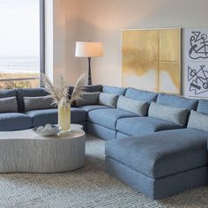 a living room filled with blue couches next to a large painting on the wall