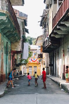 children playing soccer in an alleyway between two buildings