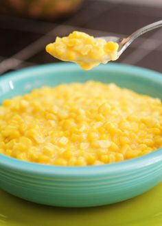 a bowl filled with corn on top of a green plate